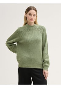 Groene geribbelde gebreide trui met een hoge kraag, lange mouwen en een relaxte pasvorm. Bevat textuurdetails en heeft een zachte, comfortabele uitstraling.