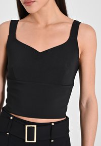 Top corto senza maniche di colore nero con design a scollo a V, realizzato in tessuto liscio. Presenta una forma aderente e dettagli minimi.