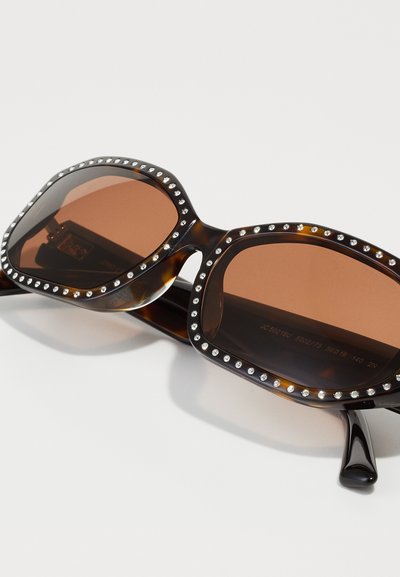 Tortoiseshell oversized sunglasses with brown lenses, adorned with silver-tone studs along the frame, featuring a glossy finish and wide sides.