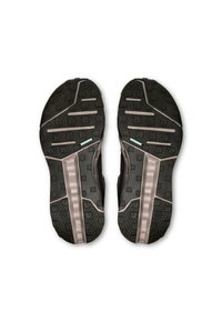 Semelles de chaussures de sport noires en caoutchouc texturé, présentant un motif de semelle géométrique, des reliefs accentués et des détails de couleur claire contrastants.