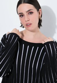 Schwarz-weißer gestreifter Pullover mit schulterfreiem Design, gerippten Bündchen, weicher Textur und lockerer Passform.