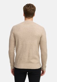 Maglione beige lavorato a maglia con scollo rotondo, maniche lunghe e orlo a coste. Texture morbida, design minimalista e senza motivi o accessori visibili.