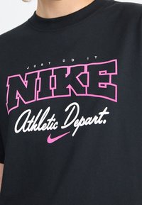 Černé bavlněné tričko s růžovo-bílým logem "NIKE", nápisem "JUST DO IT" a designem "Athletic Depart.". Kulatý výstřih a krátké rukávy.