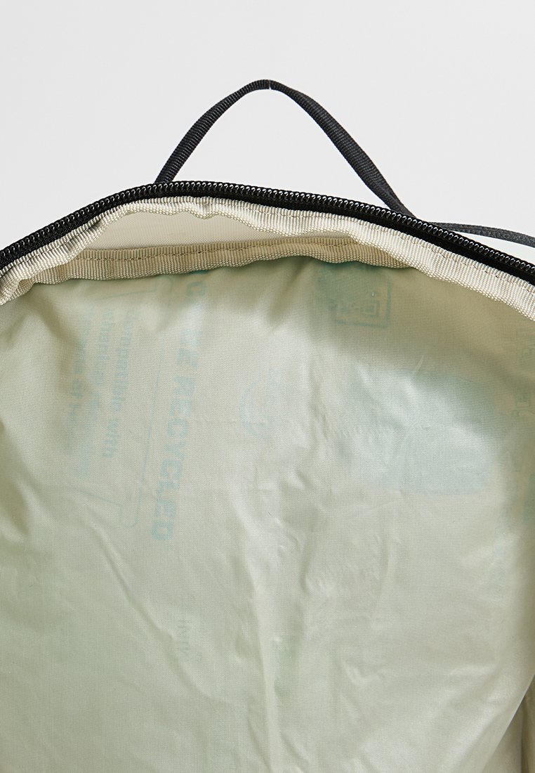 Interior de bolsa tote con cremallera, presenta un tejido verde claro con una textura suave, bordeado de ribete negro y una asa de transporte.