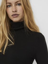 Fekete, nyúlékony anyagból készült garbó pulóver, karcsúsított szabással és texturált felülettel, magas gallérral és tiszta varrásokkal.