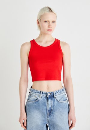 Rode cropped tanktop van ribstof, met een ronde halslijn en brede banden, gecombineerd met hooggeoriënteerde vervaagde blauwe jeans.