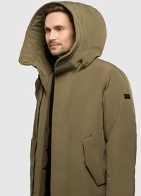 Olivově zelená zateplená parka s velkou vycpanou kapucí, bočními kapsami a zapínáním na zip. Hladká textilie s minimalistickým designem.