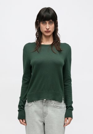 Πράσινο πλεκτό πουλόβερ με στρογγυλή λαιμόκοψη, μακριά μανίκια και ριμπ τελείωμα. Συνδυασμένο με ανοιχτό γκρι τζιν, που παρουσιάζει χαλαρή εφαρμογή.