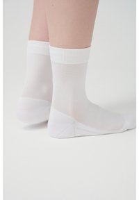 White ankle-length socks made from a thin, stretchy material. Features a ribbed cuff at the top and a smooth, seamless toe area.