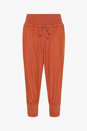 Pantalons de jogging couleur rouille avec une large ceinture élastique, des détails de cordon de serrage et des poignets froncés. Tissu doux et lisse.