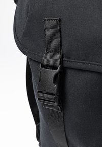 Borsa nera in tessuto con superficie texturizzata e chiusura a fibbia in plastica. La tracolla è intrecciata e regolabile per una chiusura sicura.