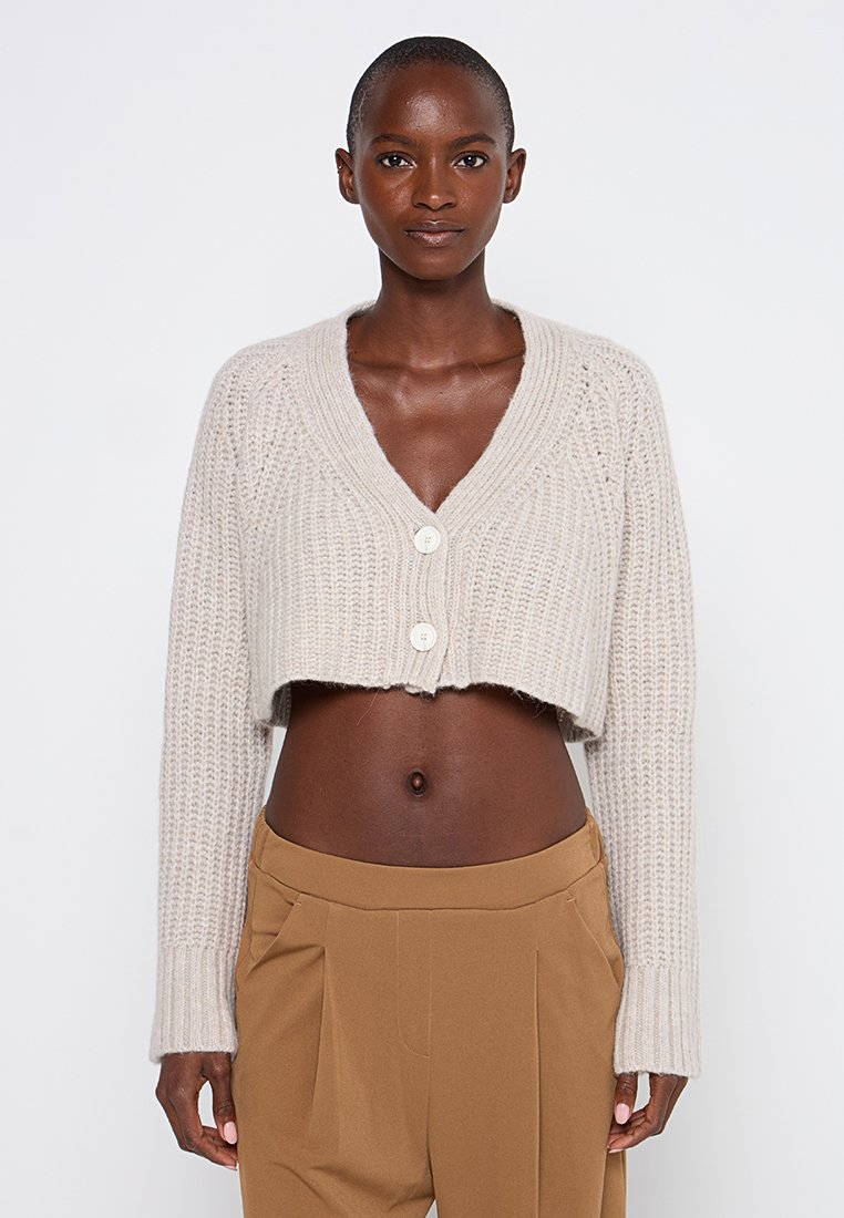 Hellbeige, kurzes Strickcardigan mit V-Ausschnitt, zwei weißen Knöpfen und strukturiertem Rippdesign. Verfügt über lange Ärmel und eine lockere Passform.