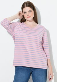 Randig långärmad t-shirt i rosa och blått med rund halsringning och avslappnad passform, tillsammans med blå jeans. Mjuk bomullsmaterial.