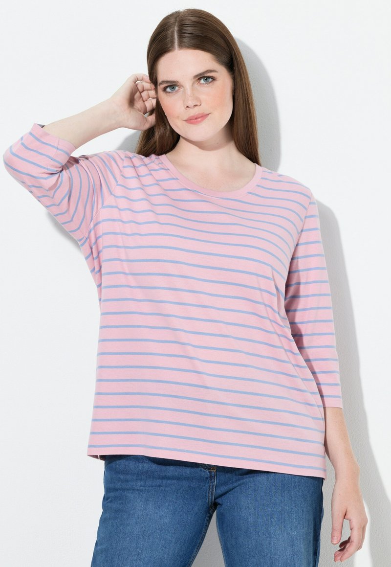 Randig långärmad t-shirt i rosa och blått med rund halsringning och avslappnad passform, tillsammans med blå jeans. Mjuk bomullsmaterial.