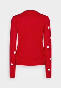 Maglione rosso lavorato a maglia con maniche lunghe e motivo a pois bianchi sulle maniche. Presenta una scollatura rotonda e orlo e polsini a coste.