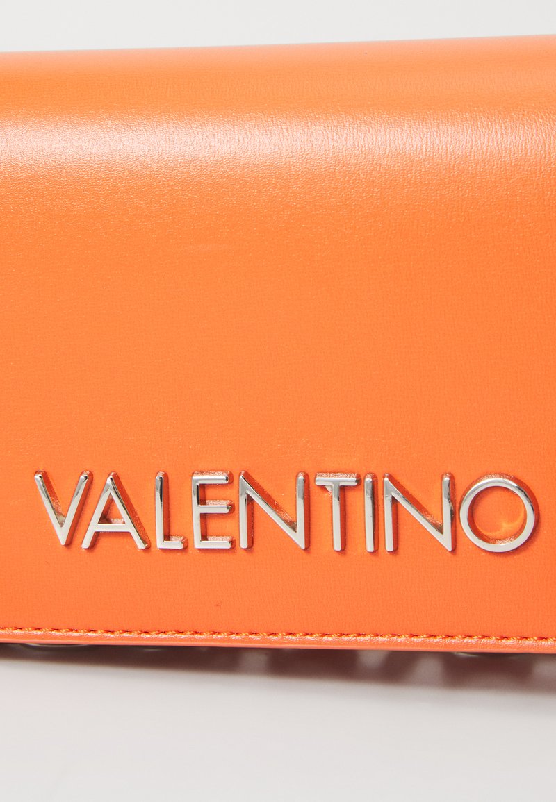 Valentino peněženka ve světlé oranžové kůži se hladkým povrchem, s kovovými prvky ve stříbrné barvě s logem značky na přední straně.