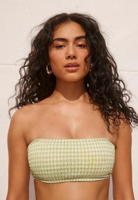 Zöld kockás bandeau top, smockolt textúrával. Egyenes nyakkivágással és testhez simuló fazonnal rendelkezik. Sima, könnyű anyag.