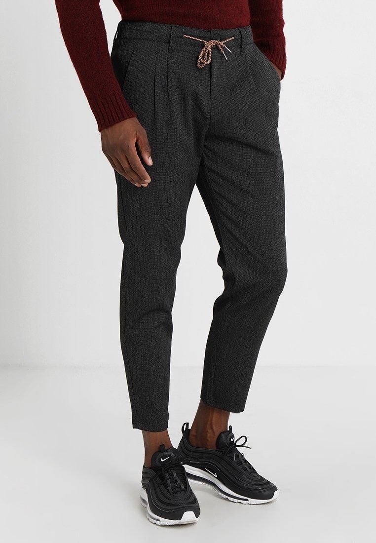 Pantaloni taper in grigio carbone con una tessitura strutturata, tasche laterali, pieghe frontali e una cintura elastica con chiusura a laccetto.