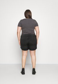 Czarne szorty z denimu o luźnym kroju, z tylnymi kieszeniami, zestawione z dopasowanym szarym t-shirtem i czarnymi botkami za kostkę.