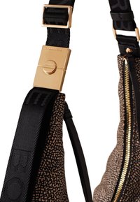 Black and tan leopard print bag with a gold clasp on a textured strap, featuring a smooth zipper and bold branding on the strap.
