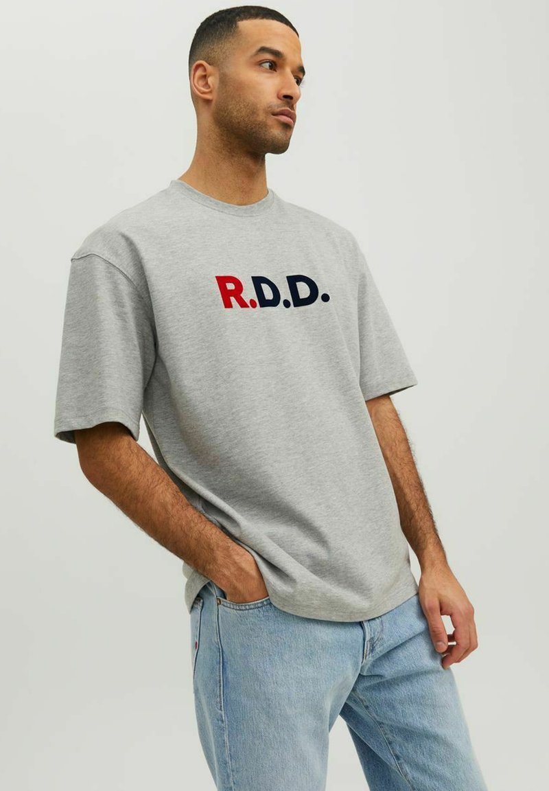 Šedé tričko s krátkym rukávom a okrúhlym výstrihom s písmenami "R.D.D." v červenej a námorníckej modrej farbe cez prednú stranu. Voľný strih, bavlnený materiál.