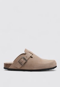 Beige Velourslederclogs mit verstellbarem Metallverschluss, offenem Rücken, runder Zehenpartie und strukturiertem Gummisohle für Halt und Komfort.