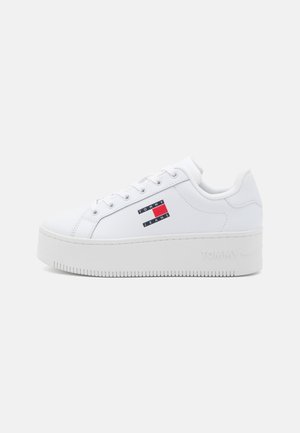 Biała platformowa trampka z wiązaniami i logo Tommy Jeans po boku, z grubą podeszwą i przeszyciami.