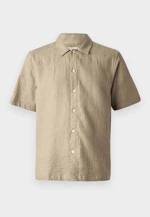 Camisa de manga corta en beige claro, de tejido texturizado. Presenta un cierre de botones en la parte delantera, un cuello puntiagudo y seis botones a lo largo de la tapa.