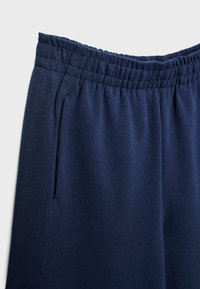 Granatowe spodnie dresowe z szerokim elastycznym pasem, miękką fakturą i kieszeniami bocznymi, zaprojektowane z myślą o komforcie i swobodzie ruchów.