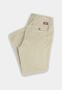 Pantalones de tergal color beige con rayas verticales, cintura elástica, un bolsillo trasero y una pequeña etiqueta de la marca. Textura suave, corte relajado.