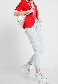 Punainen bleiseri, vaaleansiniset kapeat farkut, valkoiset sneakerit. Bleiserissä on muotoillut olkapäät; farkuissa on käännetyt lahkeet. Rintatasku on valkoinen.