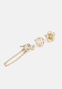 Pendientes de stud en tono dorado adornados con strass. Presentan una cadena que une dos studs, diseños florales y circulares, y un acabado pulido.