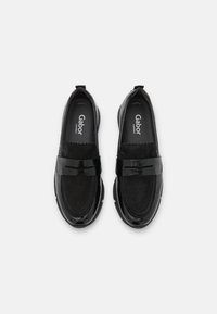 Svarta loafers i lackläder och mocka, med ett tjockt band över vampen och en vadderad innersula för komfort.