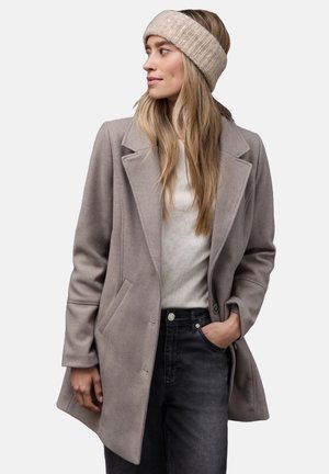 Lichtgrijze wolmix jas met een geknipt kraag en zijzakken, gedragen over een crèmekleurige trui en donker denim jeans, gecombineerd met een beige gebreid haarband.