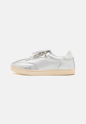Zapatilla baja de metal plateado con una textura suave, cordones blancos, suela beige y detalles de costura sutiles en la parte trasera.