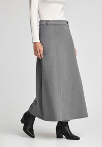 Grå denim maxikjol med rak passform, sidfickor och knappstängning i midjan. Matchas med svarta ankelboots.