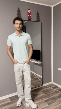 Light blue polo shirt, white pants, and gray sneakers. The background includes a mirror and a TV on a white shelf against gray walls.