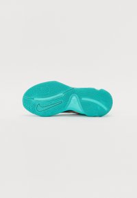 Semelle de basket couleur turquoise vif tournée vers le haut montrant un motif de bande de roulement texturé et un logo noir Nike Swoosh sur fond blanc.