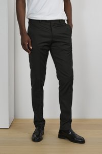 Pantalon noir ajusté en tissu lisse, doté d'une coupe slim et de détails de plis subtils, assorti à des mocassins en cuir noir.