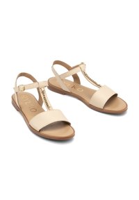 Beige nahka sandaalit sisältävät T-nauhan muotoilun, jossa on kultaketju yksityiskohta, litteä pohja ja säädettävä nilkkahihna. Tasainen pinta koko matkalta.