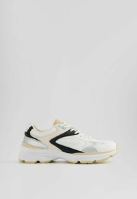 Weißer Sportschuh mit schwarzen und beigen Akzenten, strukturierten Mesh-Einsätzen und einer gepolsterten Sohle. Verfügt über eine abgerundete Zehenpartie und eine Schnürdesign.