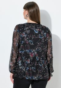 Černá průsvitná halenka s barevnými vzory motýlů a květin, dlouhými rukávy, řaseným pasem a kulatým výstřihem.