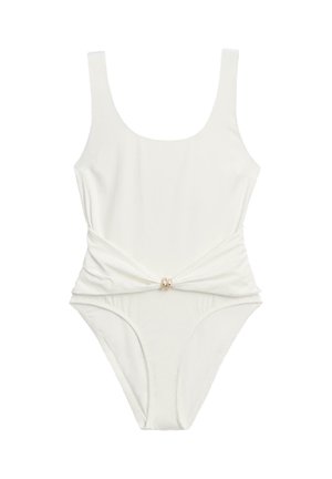 Biały jednoczęściowy strój kąpielowy z odkrytym dekoltem i skręconym detalem materiału w talii, zabezpieczonym małym złotym kółkiem.