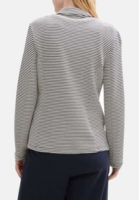 Striped long-sleeve shirt in black and white, featuring a fitted design, a soft texture, and a classic collar.