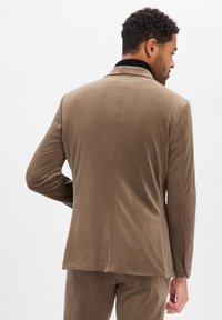 Brązowa, aksamitna marynarka z klapą z wycięciem, dopasowanym krojem i długimi rękawami. Tylny widok pokazuje gładką teksturę i dopasowane cięcie.