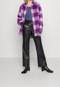 Fialová a bílá kostkovaná flanelová košile, přední knoflíky, spárovaná s černými koženými kalhotami širokého střihu a černými kozačkami na podpatku.