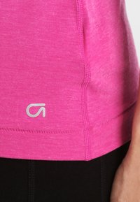 Tajt rosa träningsskjorta i texturerad tyg, med en vit logotyp vid fållen och kontrasterande svart trim.