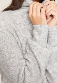 Hellgrauer Rollkragenpullover aus weichem, strukturiertem Strickstoff. Mit lockeren Ärmeln und gemütlicher, entspannter Passform.