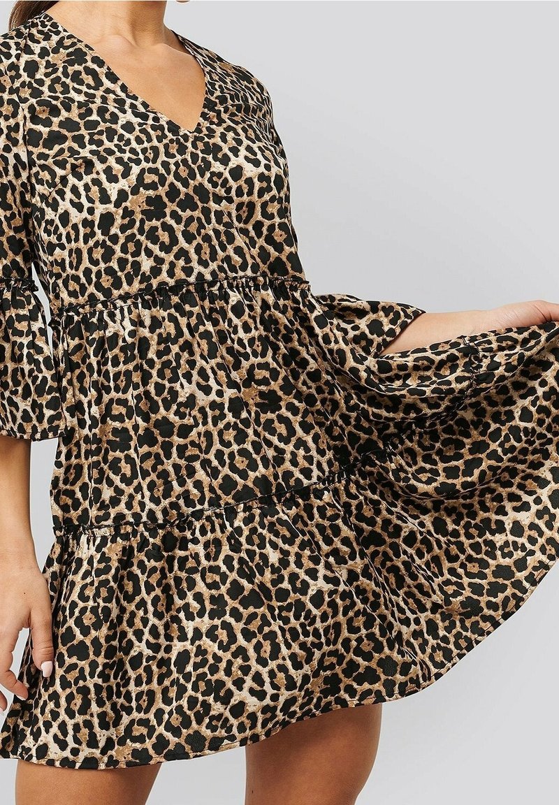 Leopardenmuster-Kleid mit V-Ausschnitt, Dreiviertelärmeln und gestuften Rüschensaum. Hergestellt aus leichtem Stoff in Beige- und Schwarztönen.