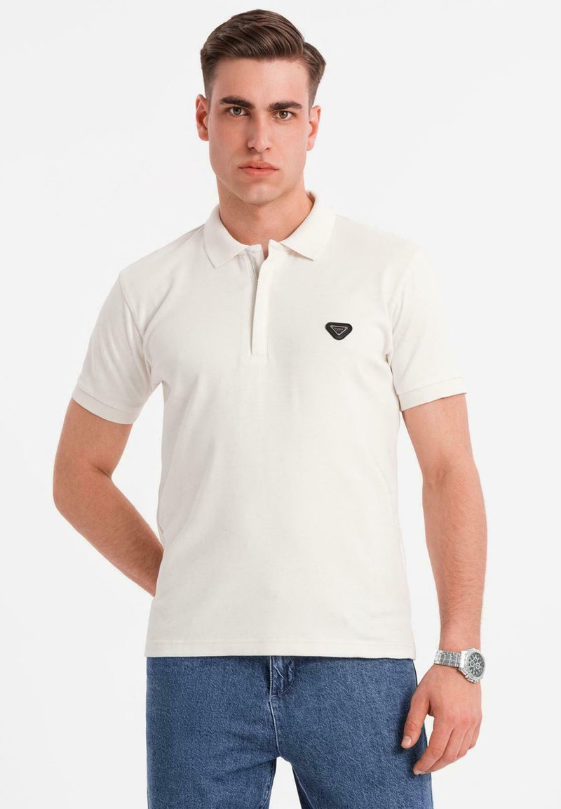 Bílé polo tričko s krátkými rukávy a tříknoflíkovou légou, na levé straně hrudi s malým černým trojúhelníkovým logem.